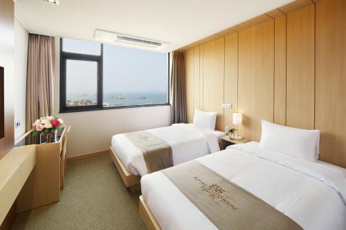 a hotel room with two beds and a large window at Royal Emporium Incheon Airport in Incheon