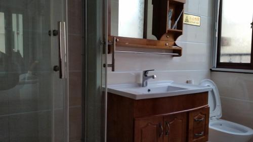 a bathroom with a sink and a shower and a toilet at 舟山朱家尖东沙东和梦园民宿 in Zhoushan