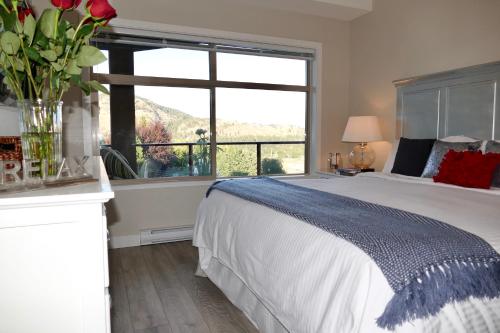a bedroom with a bed and a large window at Copper Oasis in West Kelowna