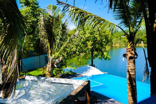 a pool with a palm tree next to a body of water at Inlaya Ratchaburi in Ratchaburi