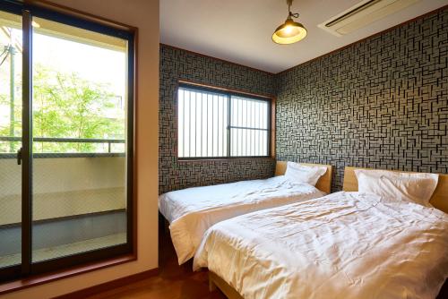 a bedroom with two beds and a window at Guesthouse Nijo Fukuro-Tei in Kyoto