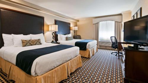 um quarto de hotel com duas camas e uma televisão de ecrã plano em Best Western Plus Puyallup Hotel em Puyallup
