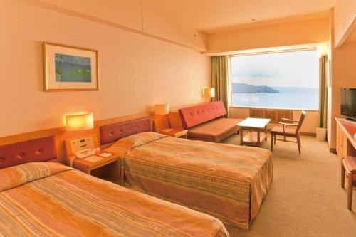 a hotel room with two beds and a television at Kussharo Prince Hotel in Teshikaga