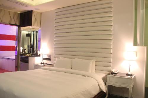 a bedroom with a large white bed and two lamps at Kai-Hong Motel in Longtan