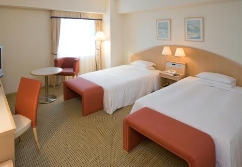 a hotel room with two beds and a table at Hotel Hewitt Koshien in Nishinomiya