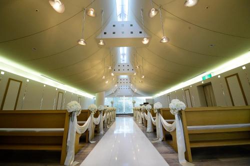 a row of chairs in a church with white flowers at Hotel Hewitt Koshien in Nishinomiya