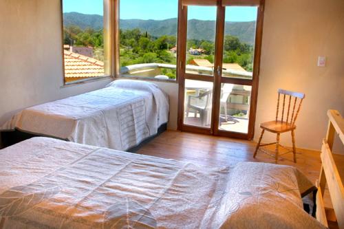 a bedroom with two beds and a large window at Cabañas Wairoa Haus in Villa General Belgrano
