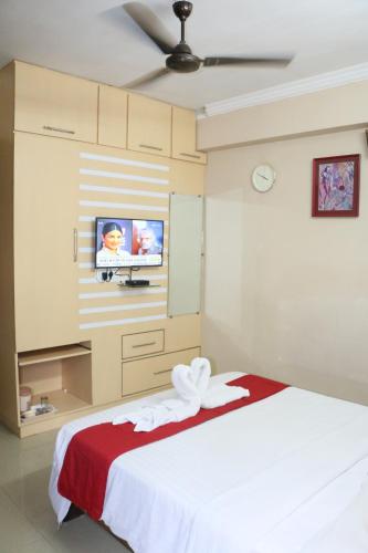 a bedroom with a white bed and a flat screen tv at Hotel Akshaya in Visakhapatnam