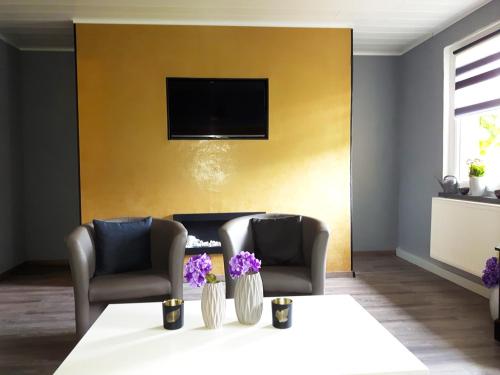 a living room with two chairs and a table with purple flowers at Ferienwohnung Talblick in Eisenach