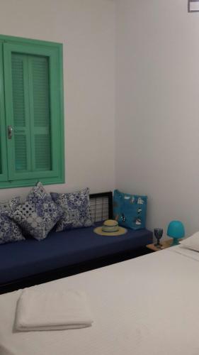 a room with a bed with pillows and a green window at Galanopetra RHODES GREECE in Rhodes Town