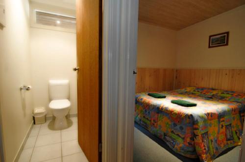 uma casa de banho com uma cama e um WC num quarto em Mallacoota Log cabins em Mallacoota
