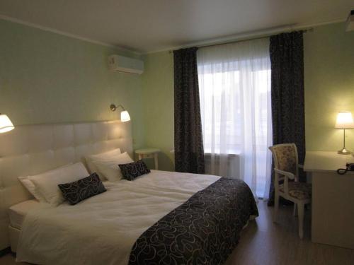 Un dormitorio con una gran cama blanca y una ventana en Avantazh Hotel, en Saratov