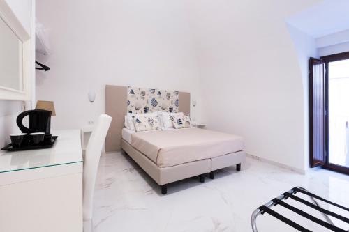 a white bedroom with a bed and a desk at Holiday Sorrento Center in Sorrento