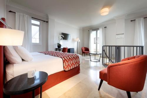 pokój hotelowy z łóżkiem i krzesłem w obiekcie Eurostars Regina w Sewilli
