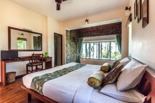 a bedroom with a large bed and a desk at Sitaram Mountain Retreat in Munnar
