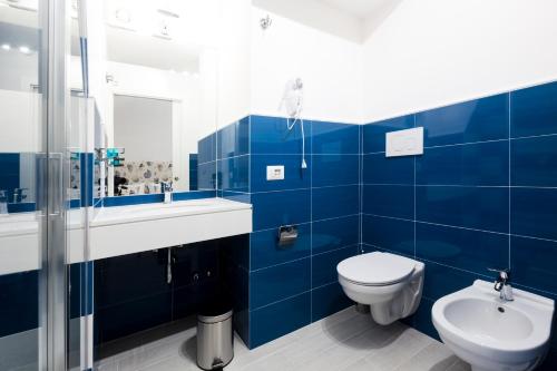 La salle de bains est pourvue de carrelage bleu, de toilettes et d'un lavabo. dans l'établissement Holiday Sorrento Center, à Sorrente