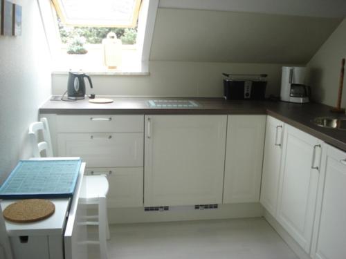 a kitchen with white cabinets and a sink and a window at Ferienwohnung Möwennest in Timmendorfer Strand