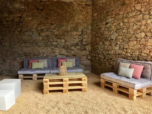 two couches and a table in front of a stone wall at Hostal Can Xicu in Capmany