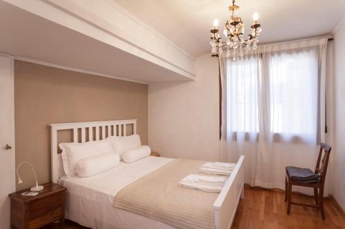 a white bedroom with a bed and a chandelier at Palazzo Valmarana Braga in Vicenza