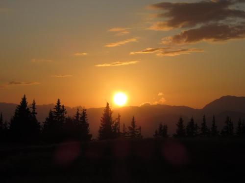 a sunset in the mountains with trees in the foreground at Haus Anni in Radstadt