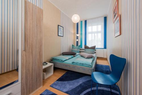 a small bedroom with a bed and a blue chair at Ferienwohnung Moderne Mitte in Eisenach