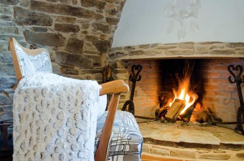 a fireplace with a chair in front of a brick fireplace at Complejo Rural Lar de Vies in A Pontenova