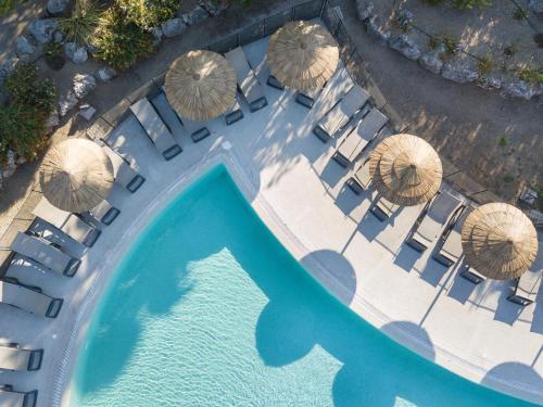 une vue aérienne d'une piscine avec des chaises et des parasols dans l'établissement Hotel Club Le Capet, à Sainte-Maxime
