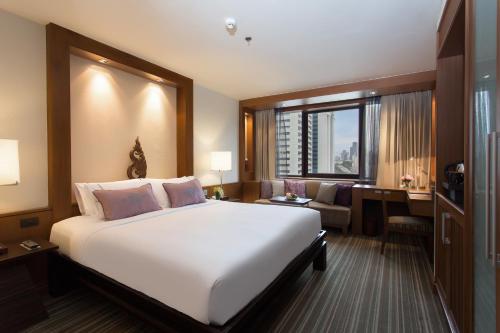 een slaapkamer met een groot wit bed en een bureau bij The Sukosol Hotel in Bangkok