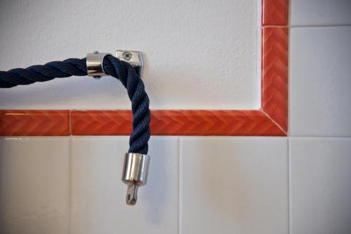 a hose hooked up to aaucet on a tiled wall at B&B Villa Ines in Leuca
