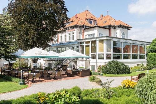 une grande maison avec des tables et des chaises en face de celle-ci dans l'établissement Parkhotel Bilm im Glück am Stadtrand Hannovers, à Sehnde