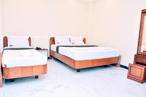 two beds sitting next to each other in a room at Hotel Raams Park in Tiruchchirāppalli
