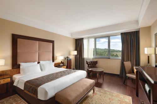 a hotel room with a large bed and a window at Ramada Plaza by Wyndham Gevgelija in Gevgelija