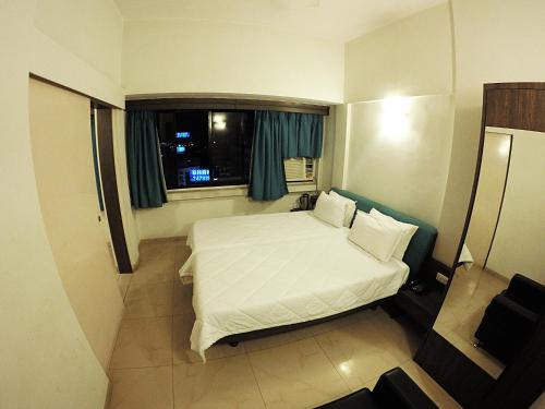 um quarto com uma cama branca e uma janela em Tex Palazzo Hotel em Surat