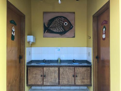ein Badezimmer mit einem Waschbecken und einem Fischgemälde an der Wand in der Unterkunft Pousada Rosa dos Ventos in Delfinópolis