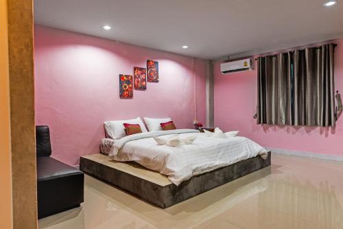 a bedroom with a pink wall with a bed at The Guest Hotel Krabi in Krabi town