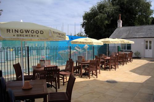 a row of tables and chairs with umbrellas on a patio at The Swan @Old Stratford in Milton Keynes