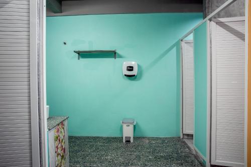 a bathroom with a blue wall with a trash can at The Guest Hotel Krabi in Krabi town
