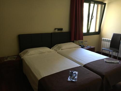 a hotel room with two beds and a window at Hotel Dom in Organyà