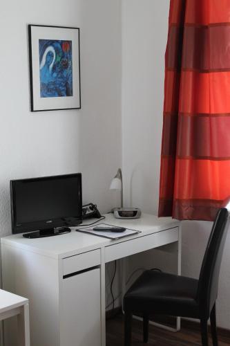 a white desk with a computer and a chair at Zum Löwen in Bad Homburg vor der Höhe