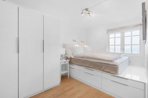 a white bedroom with a bed and a window at Øyjorden Apartment in Bergen