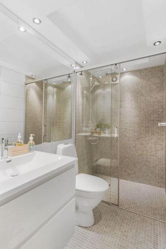 a bathroom with a toilet and a glass shower at Øyjorden Apartment in Bergen