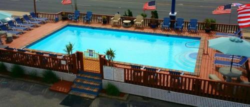 a large swimming pool with chairs and an umbrella at Sea Horse Motel in Brant Beach