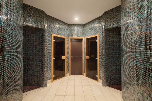 a bathroom with blue tiled walls with glass doors at Ramada Plaza by Wyndham Gevgelija in Gevgelija