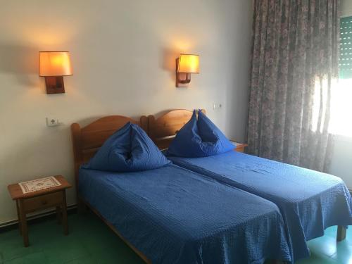 two beds in a hotel room with blue sheets at Pension Casa Austria in Calella