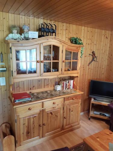 Il comprend une cuisine avec des placards en bois et une télévision. dans l'établissement Ferienwohnung Duinli, à Fiesch