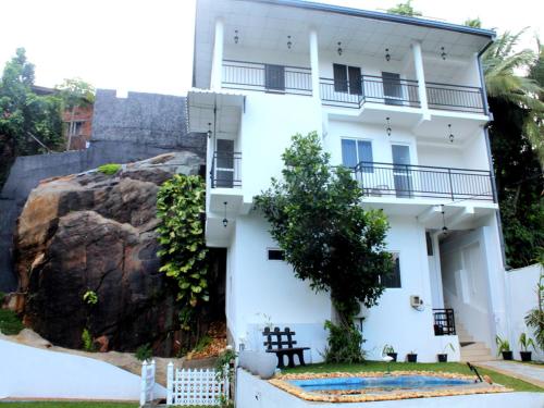 a white building with a rock in front of it at Elliot Nature Resort in Galle