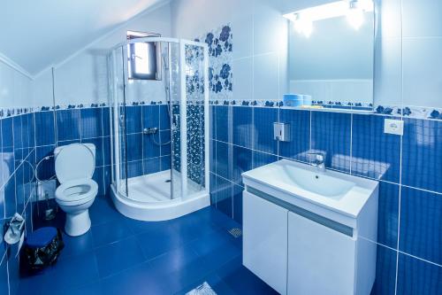 a blue tiled bathroom with a toilet and a sink at Conacul lui Bulică in Novaci-Străini