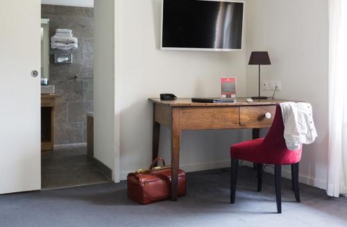 un bureau en bois avec un fauteuil rouge et une valise rouge dans l'établissement Domaine de Cabasse, à Séguret