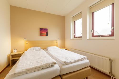 a bedroom with two beds and two windows at Center Parcs Sandur Emmen in Emmen