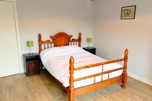 a bedroom with a wooden bed with white sheets at Harbour Bar Apartment in Greencastle